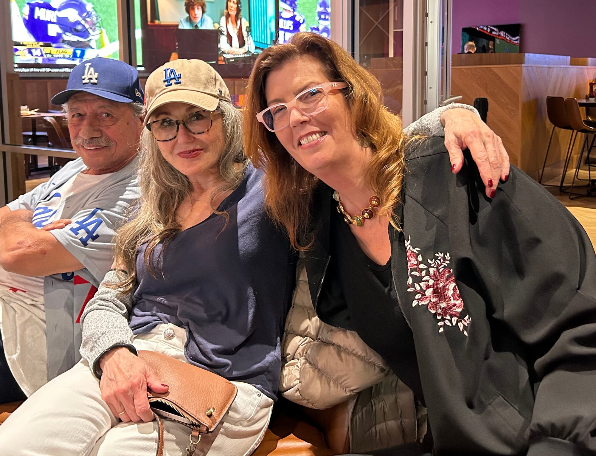 Edward James Olmos wearing a Dodgers cap, Mary McDonnell weearing a Dodgers cap and Maureen Ryan, all smiling